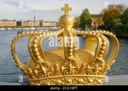 Gold Crown on bridge in Stockholm at Skeppsholmbron with boats and Strandvagen in background. Stock Photo