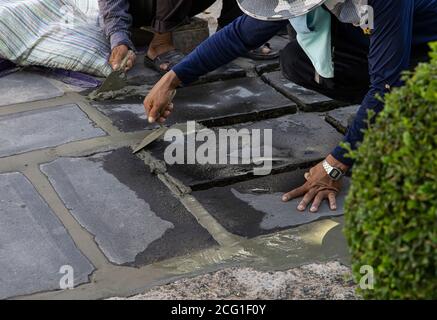 Construction workers are paving the sidewalk stone with cement. Stock Photo