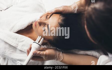Anti aging procedures for facial skin in a modern spa salon done to a brunette woman with new apparatus Stock Photo