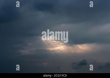 Rays of light shining through dark clouds, dramatic sky with cloud. Ray's penetrating through clouds in the sky Stock Photo