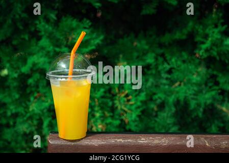 Orange lemonade in plastic glass, cooling fruit drink. Refreshing summer drinks. Plastic cup you can take with. Stock Photo