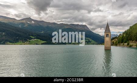 Beautiful panoramic view of the top of the old bell tower of Curon (Graun) emerging from the waters of the Resia lake, South Tyrol, Italy Stock Photo