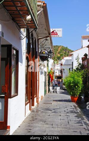 View along a traditional village shopping street with bars and restaurants, Benahavis, Spain. Stock Photo