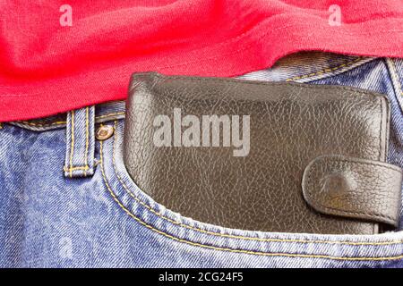 Leather black wallet in the pocket of jeans, close-up, Black leather wallet in blue jeans, denim background texture. Stock Photo