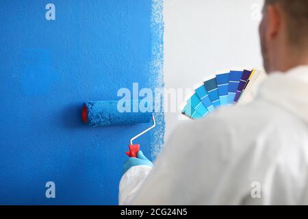 Craftsman Holds Roller And A Color Palette And Paints White Wall Blue   Craftsman Holds Roller And A Color Palette And Paints White Wall Blue 2cg24n5 