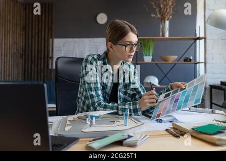 Female interior designer working in office with color palette. Architect select colors for building using color swatches, searching new ideas for Stock Photo