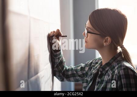 Close-up portrait of beautiful woman concentrated on work. Architect working in office with blueprints. Engineer sketching a construction project Stock Photo