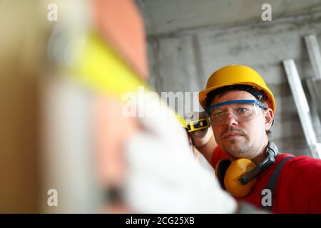 Builder measuring wall level with roulette tape Stock Photo