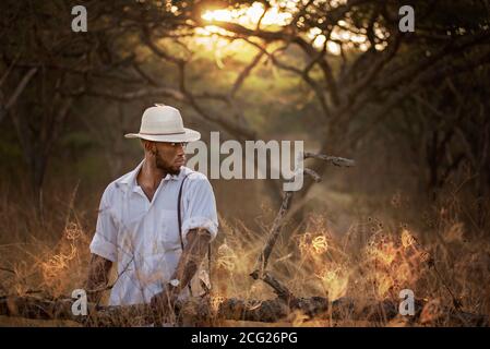 african gentleman in the african bush with bush hat in the grass Stock Photo