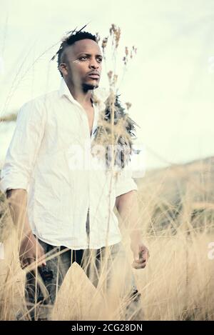 african gentleman in the african bush with bush hat in the grass Stock Photo