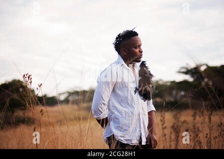 african gentleman in the african bush with bush hat in the grass Stock Photo