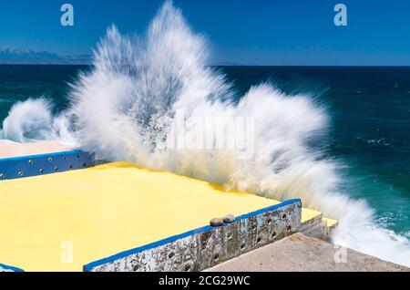 Sea spray splashes against the pier by the sea Stock Photo