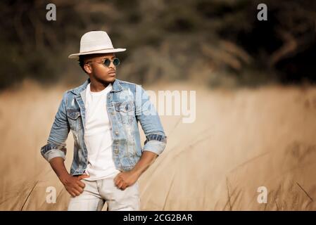 african gentleman in the african bush wearing a hat and sun glasses in the bright sun Stock Photo