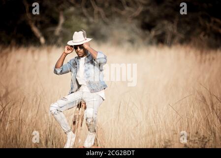 african gentleman in the african bush wearing a hat and sun glasses in the bright sun Stock Photo