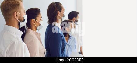 Company workers wearing protective face masks standing together during work meeting Stock Photo