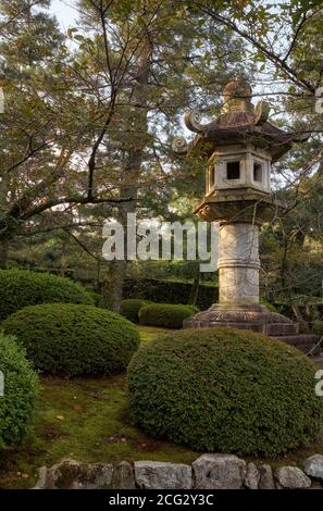 The view of the traditional pedestal Kasuga-doro stone lantern in the garden of the central Kyoto. Japan Stock Photo
