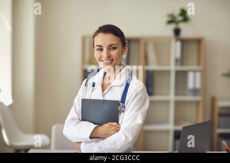 Young smiling doctor therapist standing and looking at camera in medical clinic Stock Photo