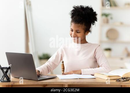 African Girl Doing Homework On Laptop Studying Online At Home Stock Photo