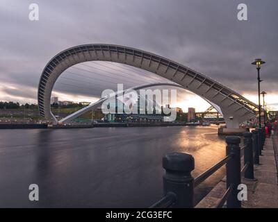 The Gateshead Millenniumm Bridge spanning the River Tyne captured in its tilted position at dusk from Newcastle quayside.