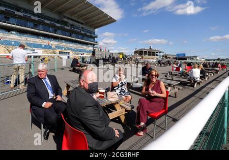 Racegoers take their seats at benches near the finishing post during day one of the William Hill St Leger Festival at Doncaster Racecourse. Stock Photo
