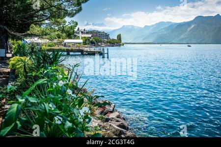 Montreux shoreline with flowers and Lake Geneva view with Alps mountains in background during sunny summer day in Montreux Vaud Switzerland Stock Photo