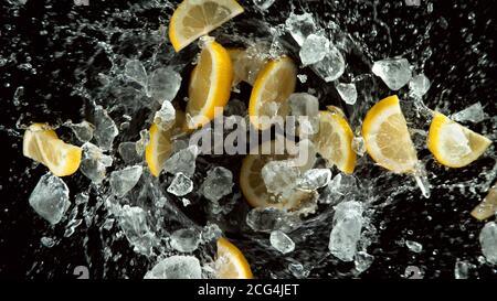 Freeze motion of lemons slices with ice cubes and water splashes, isolated on black background Stock Photo