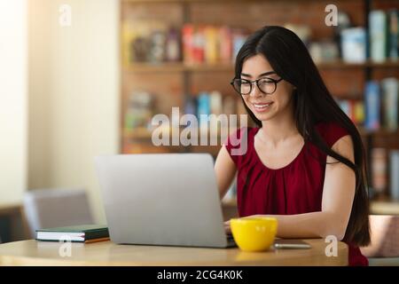 Smiling Asian Student Girl Preparing Exam With Laptop In Cafe, Studying Online Stock Photo