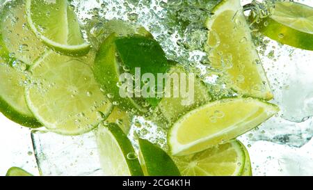 Lime Slices with ice cubes falling deeply under water isolated on white background Stock Photo