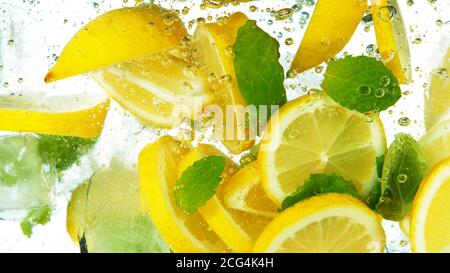 Lemon Slices with ice cubes and leaves falling deeply under water isolated on white background Stock Photo