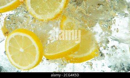 Lemon Slices with ice cubes falling deeply under water isolated on white background Stock Photo