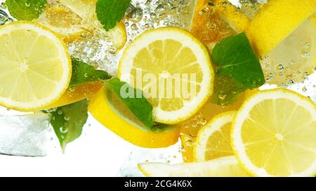 Lemon Slices with ice cubes and leaves falling deeply under water isolated on white background Stock Photo