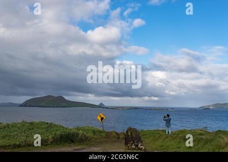 Tourist taking photo of great blasket islands from cliffs on the Dingle peninsula, County kerry, Ireland Stock Photo