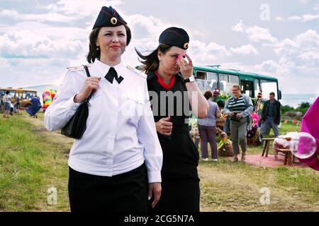 Two smiling young women in police uniform walk along the road while on duty at the music and ethnic festival Karatag. Stock Photo