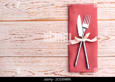 Knife and fork laying on a linen napkin. Stock Photo
