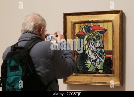 A visitor takes a photograph Weeping Woman (1937), by Pablo Picasso, on display during a press preview of the 'Picasso and Modern British Art' exhibition, at Tate Britain in London. Stock Photo