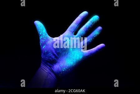 UV Ultraviolet light on a hand illustrating the effect of bacteria and viruses on asurface that has not been washed showing the importance of good hyg Stock Photo