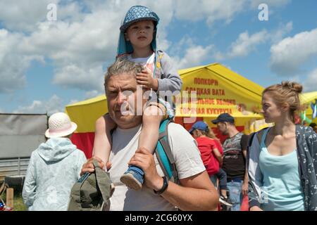 Grandfather grandson carries on his shoulders during the ethnic festival Karatag on the shore of a Large lake. Stock Photo