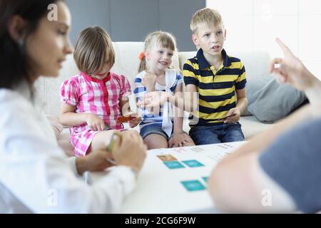 Adults and children sit around a table on which playing cards are located boy argues and discusses the rules with an adult. Stock Photo