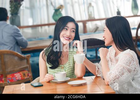 Young girlfriends chat in a coffee shop Stock Photo