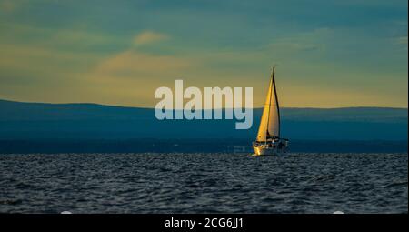 setting sun lights up the sails of sailboat on Lake Champlain, Burlington, Vermont Stock Photo