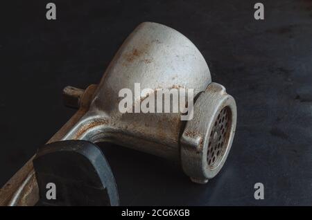Manual vintage meat grinder on a black background. Hand tool for grinding various products. Antique kitchen utensils. Stock Photo