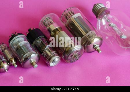 Various vacuum tubes on a pink background. A group of random radio tubes. Types of obsolete electrical parts. Selective focus. Stock Photo