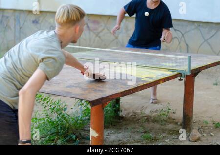 Two men are playing ping pong outdoors. Street sports competitions. Active lifestyle. Real people. Selective focus. Stock Photo