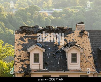 Morgantown, WV - 8 Spetember 2020: Roofing contractor removing the old tiles from townhouse roof before replacing with new shingles Stock Photo