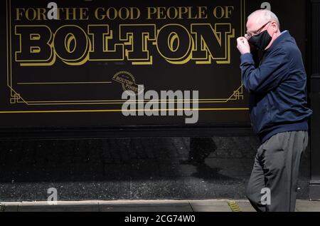 Bolton, Lancashire, 9th September 2020. The people of Bolton face their first full day of a new stricter lockdown today. Pubs, bars and restaurants are only allowed to serve a take away service, while it is not allowed to meet anyone from outside your family. A man in a protective masks walks past a sign on local pastie makers Carrs shop. Credit: Paul Heyes/ Alamy Live News Stock Photo