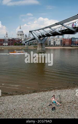 Busker in front of the Millennium Bridge crossing the River Thames with St Paul's Cathedral in the background, City of London, England. Stock Photo