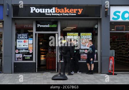 Bolton, Lancashire, 9th September 2020. The people of Bolton face their first full day of a new stricter lockdown today. Pubs, bars and restaurants are only allowed to serve a take away service, while it is not allowed to meet anyone from outside your family. People queue outside the Pound Bakery, Newport Street, Bolton. Credit: Paul Heyes/ Alamy Live News Stock Photo
