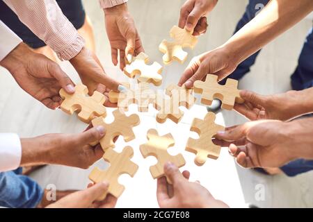 Company employees playing game and joining pieces of jigsaw puzzle during team building activity
