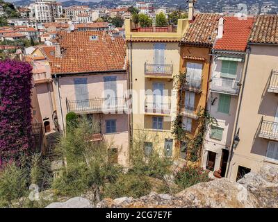 View from the stone wall on the hill over the atmospheric old traditional houses with red tiled roofs, wooden sun blinds, open balconies, flowerpots. Stock Photo