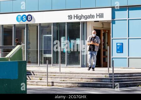 A man in a face mask sanitises his hands as he exits the TSB bank in Archway, now open since the easing of lockdown restrictions, London, UK Stock Photo